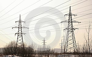 High-voltage towers, transmission line in winter city background.