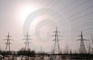 High-voltage towers, transmission line in winter city background.