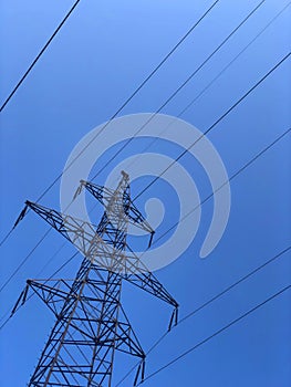 High voltage transmission line electric cables. High voltage tower against a clear blue sky background. Powerline