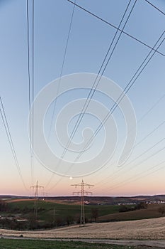 High-voltage transmission lines converging on the horizon at twilight
