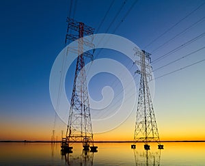 High voltage transmission lines crossing Wheeler Lake at dusk near Athens AL. Electricity pylons at sunset. Power and energy