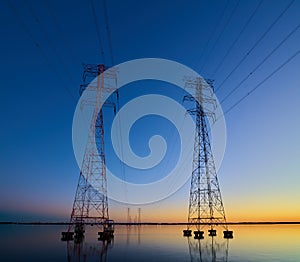 High voltage transmission lines crossing Wheeler Lake at dusk near Athens AL. Electricity pylons at sunset. Power and energy