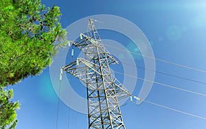 High-voltage transmission pylon against a blue sky, sun and green branches. Green energy concept