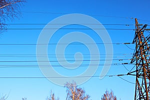 High voltage transmission tower line against blue sky, bottom view. iron construction.