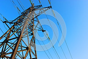 High voltage transmission tower line against blue sky, bottom view. iron construction.