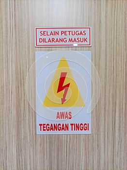 High-voltage warning sign or signboard made of acrylic is placed in front of the door of the control room