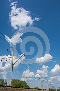 High-voltage wire along railway under blue sky