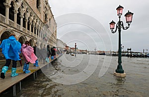 high water in Venice in Italy and people walking over the walkways and ancient building