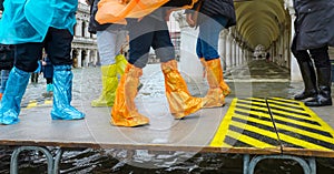high water in Venice in Italy and people walking over the walkways with waterproof gaiters on feet