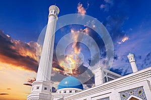 high white minaret and blue dome of modern Islamic Masjid Minor Mosque in Tashkent in Uzbekistan on background of sunset