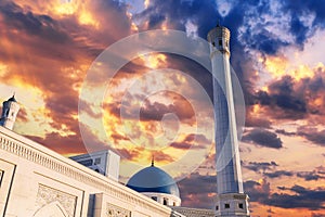 high white minaret and blue dome of modern Minor Mosque in Tashkent in Uzbekistan on background of beautiful sunset sky