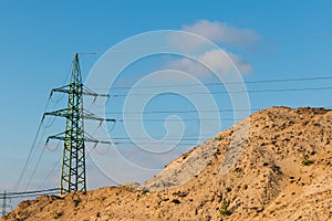 High woltage tower in a evening sunlight behind huge stack of sa