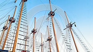 High wooden masts and historical ship rigging against blue sky