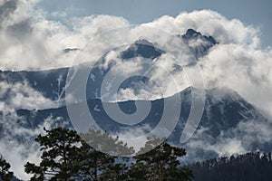 The highest peaks of the mountains make their way through the clouds. Stones and rocks. Hiking in the mountains.