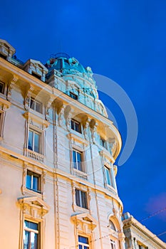 Highest point of a baroque building illuminated with yellow light on a blue night sky