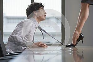 Highheeld Businesswoman Stepping On Businessman's Tie