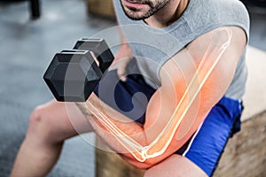 Highlighted arm of strong man lifting weights at gym