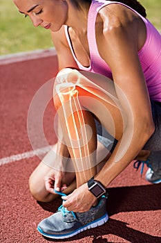 Highlighted bones of woman tying shoe lace on race track