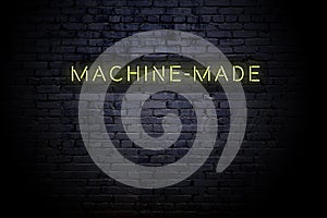 Highlighted brick wall with neon inscription machinemade