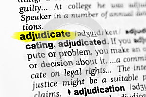 Highlighted English word `adjudicate` and its definition in the dictionary photo