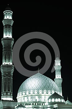 Highlighted white dome and minarets of the mosque against the dark sky. photo
