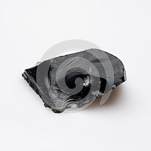 A highly polished black obsidian fragment displaying a sharp, glass-like surface and a distinctive conchoidal fracture pattern