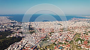 Highly populated big Greek town with famous white-washed houses and orange rooftops. Aerial view. Beautiful weather. photo