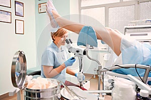 Highly qualified doctor examining woman with colposcope.