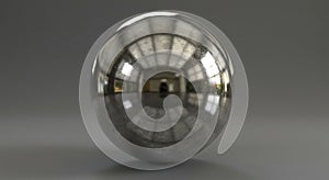 A highly reflective metallic sphere placed on a smooth, gray surface. The sphere