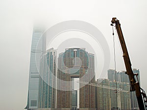 Highrise buildings- skyscraper and construction crane in foggy weather