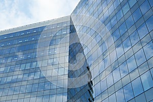 Highrise glass building with sky and clouds reflection. geometric shapes