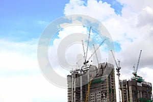 Highrise tower crane and new unfinished residential townhouse under construction, buildings front view. Urban development theme.