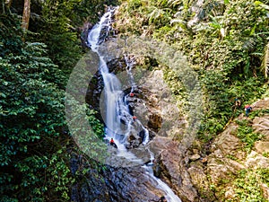 Hight waterfall with 3 man in the green tropical forest