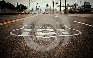 Highway 101 sign painted on the black asphalt road with city diffused in the background.