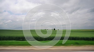 Highway along green meadows fields, cloudy weather in summer, overcast. Overtaking passing of lorry cargo truck. View