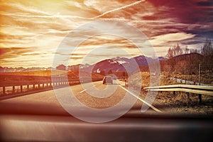 Highway in the Alps. view from inside car, sunset or sunrise