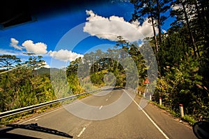 Highway Bend against Hilly Country land Blue Cloudy Sky