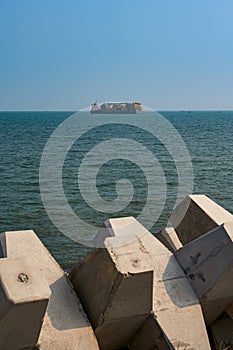 Highway breakwaters and giant freighters at sea in the distance