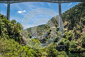 Highway bridge framing wild nature with various types of trees on the banks and Philippine bridge over the ZÃÂªzere river, PORTUGAL photo