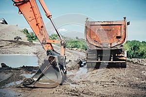 Highway construction site details with excavator bucket and dumper truck