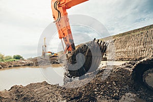 Highway construction works with excavator scoop loading earth and soil