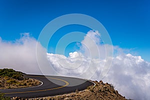 Highway curve above fluffy white clouds and blue sky