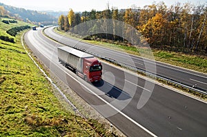 The highway between deciduous forests with leaves in fall colors, the highway ride three trucks