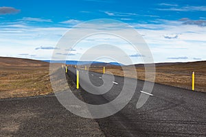 Highway through gravel lava field landscape under a blue summer