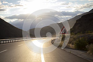 Highway heading towards sunset. Sunlight reflects on the road.