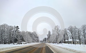 highway with horizon on blue sky and clouds in the daytime at winter with snow covered trees.