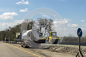 Highway intercity new road construction site with many heavy machinery steamroller, water tanker truck and paver tractor