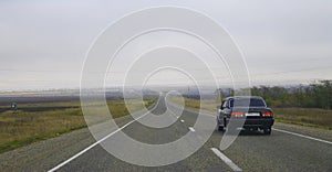 Highway landscape with moving cars at daytime by misty road