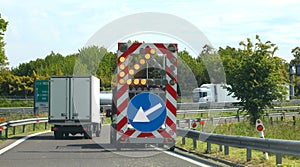 Highway maintenance truck with the road sign with the arrow to signal the narrowing of the roadway