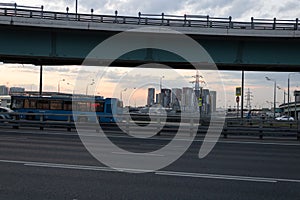 Highway in Moscow with bus and cars. Bridge, lampposts and new buildings in the background.